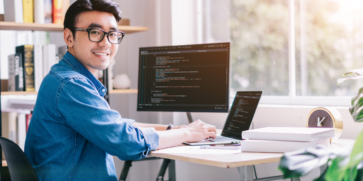 A smiling coding web developer at his computer